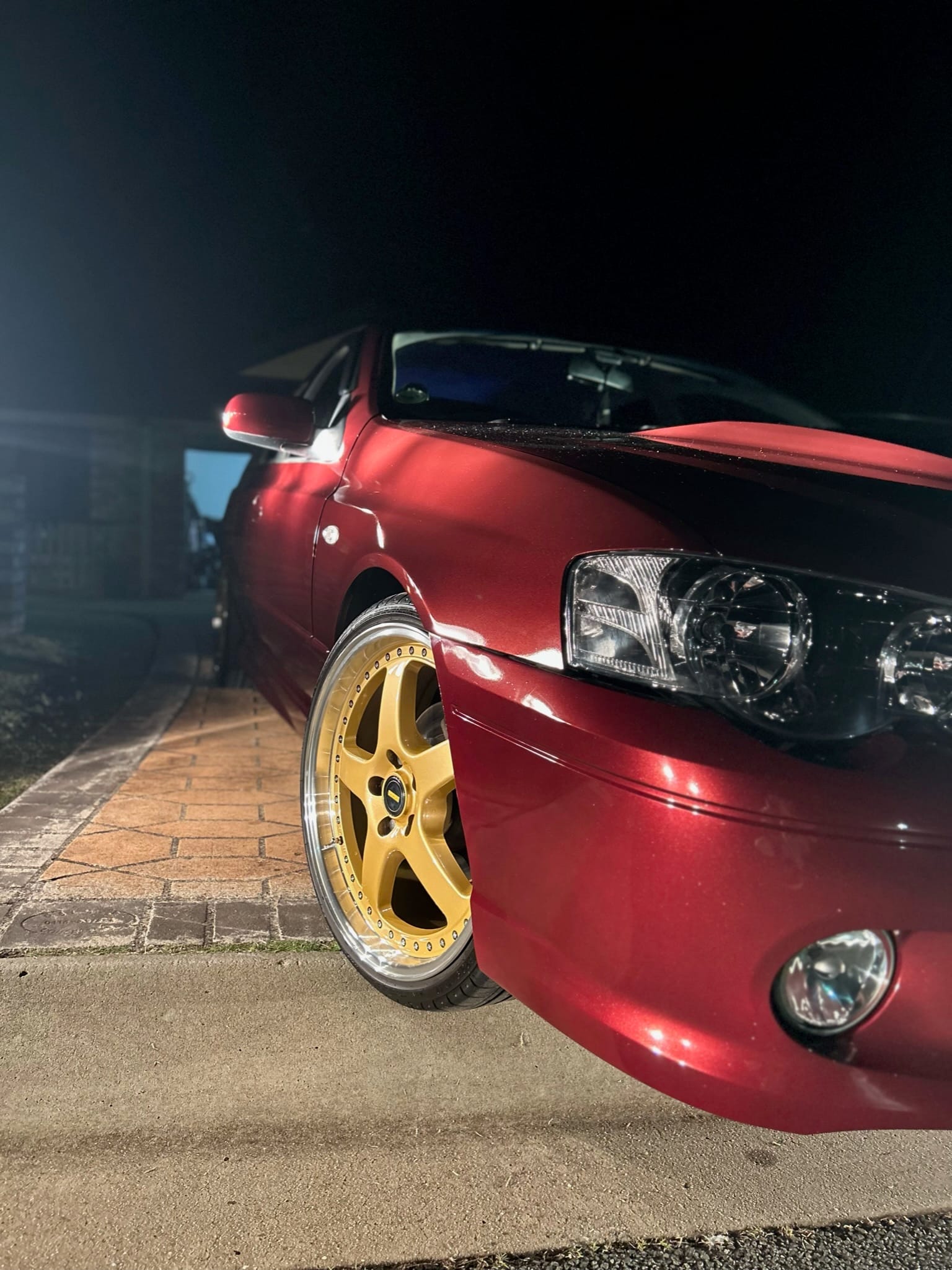 Red car with gold wheels detailed and photographed at night